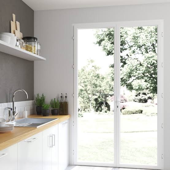 Porte-fenêtre PVC blanche à deux vantaux donnant sur le jardin